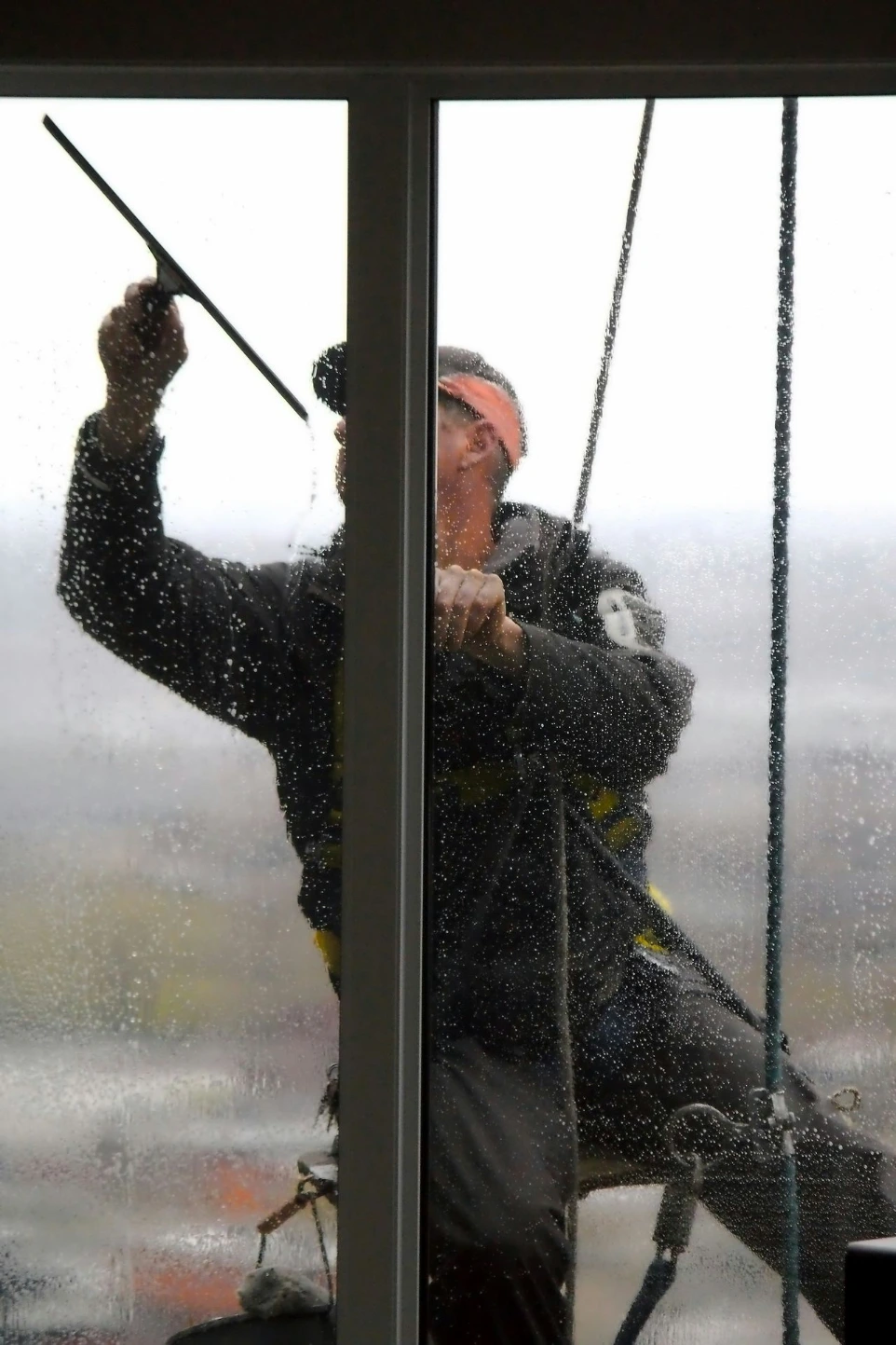 A window washer cleans a glass pane.